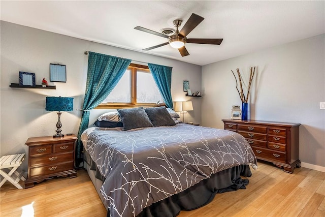 bedroom with a ceiling fan, wood finished floors, and baseboards