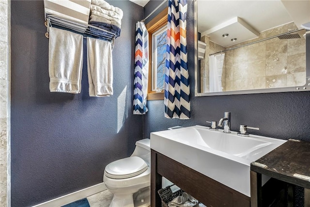 bathroom with toilet, vanity, and a textured wall