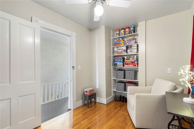 living area featuring light wood-style flooring, a ceiling fan, and baseboards