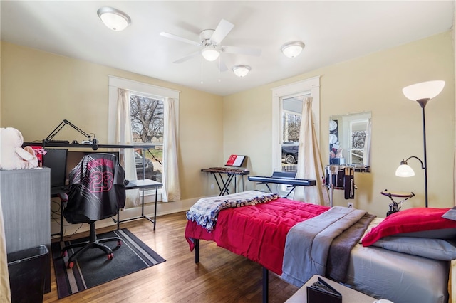 bedroom with a ceiling fan, baseboards, and wood finished floors