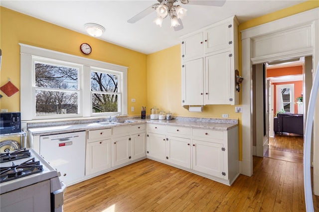 kitchen with light wood finished floors, ceiling fan, white appliances, white cabinetry, and a sink