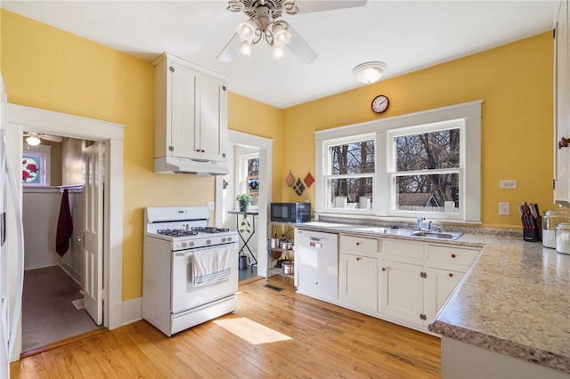 kitchen with light wood finished floors, under cabinet range hood, white cabinets, white appliances, and a sink