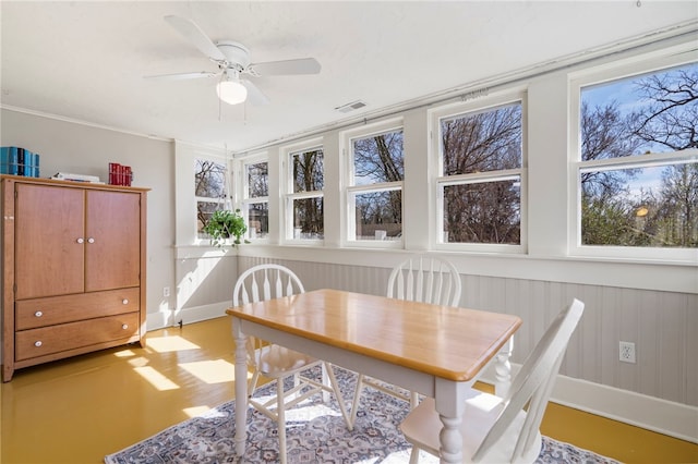 dining room featuring visible vents, plenty of natural light, ceiling fan, and wainscoting