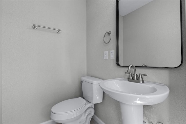 half bathroom featuring baseboards and toilet