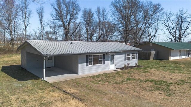 view of front of home with a front lawn, a carport, fence, and metal roof