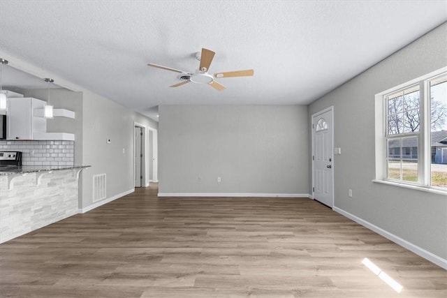 unfurnished living room with visible vents, baseboards, light wood-style floors, and ceiling fan