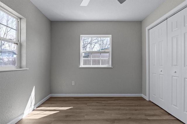 unfurnished bedroom featuring ceiling fan, wood finished floors, a closet, and baseboards