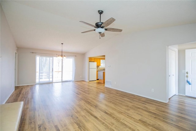 unfurnished living room featuring visible vents, baseboards, lofted ceiling, light wood-style floors, and ceiling fan with notable chandelier