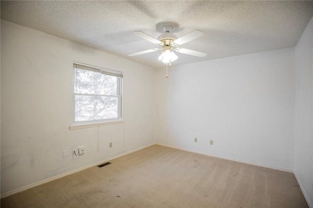 spare room with a ceiling fan, baseboards, visible vents, a textured ceiling, and light colored carpet