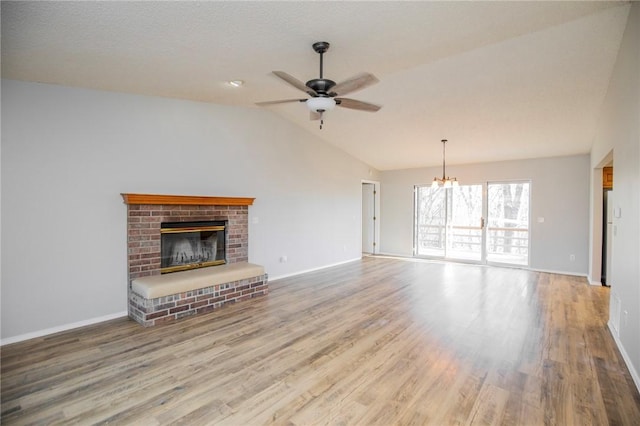 9 Cromer Dr, Bella Vista, AR 72715 - unfurnished living room featuring a brick fireplace, ceiling fan with notable chandelier, vaulted ceiling, and wood finished floors