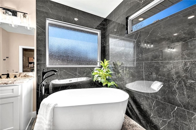 full bath featuring vanity, tile walls, and a freestanding tub