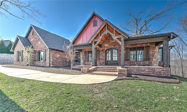 view of front of house with brick siding, french doors, a front yard, and board and batten siding