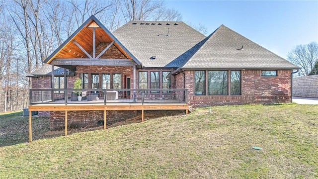 rear view of property with a wooden deck, brick siding, and a lawn