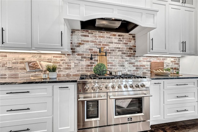 kitchen featuring white cabinetry, custom exhaust hood, double oven range, and dark stone counters