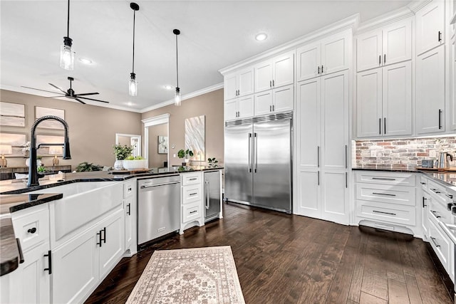 kitchen featuring a sink, decorative light fixtures, appliances with stainless steel finishes, and crown molding