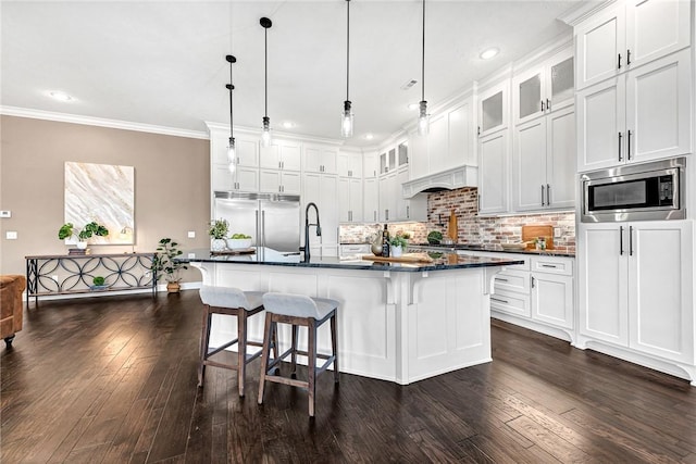 kitchen featuring a kitchen breakfast bar, white cabinets, crown molding, glass insert cabinets, and built in appliances