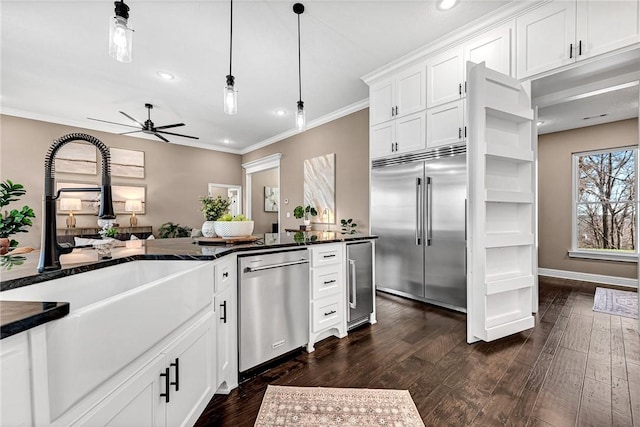 kitchen with dark wood finished floors, a sink, white cabinets, appliances with stainless steel finishes, and crown molding