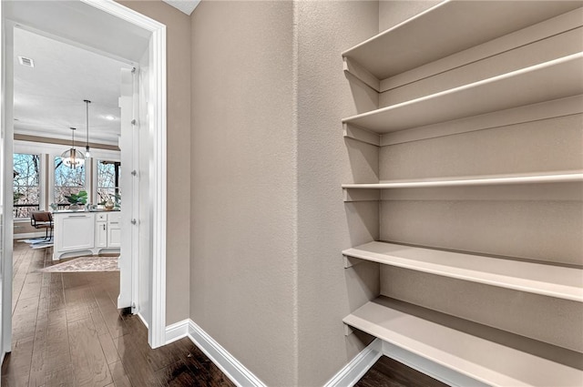 hall with dark wood finished floors, an inviting chandelier, and baseboards