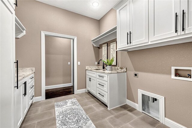 laundry room featuring hookup for an electric dryer, light tile patterned flooring, cabinet space, a sink, and washer hookup