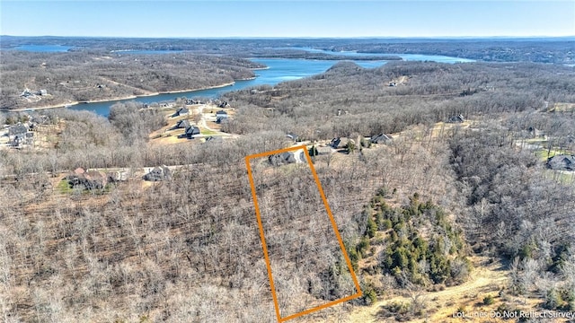 drone / aerial view featuring a wooded view and a water view