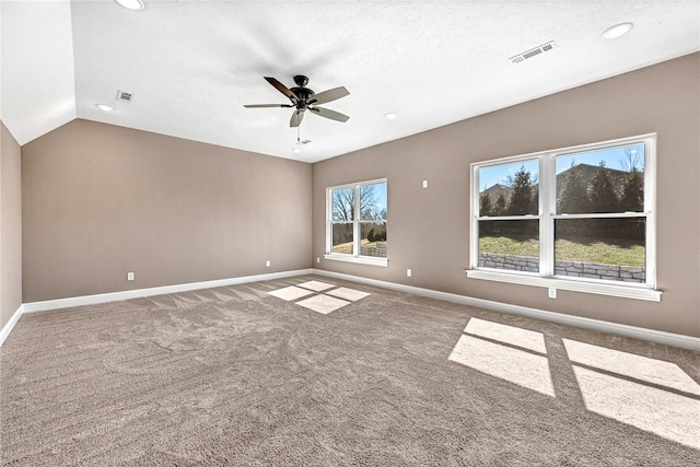 carpeted empty room with visible vents, baseboards, lofted ceiling, and ceiling fan