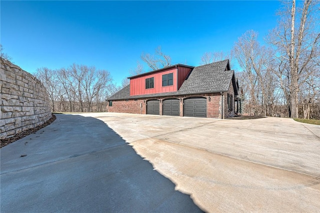 view of home's exterior with brick siding, board and batten siding, driveway, and a shingled roof