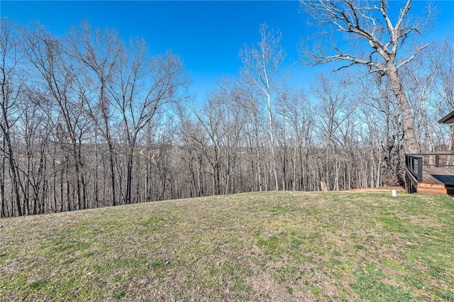 view of yard featuring a view of trees and a deck