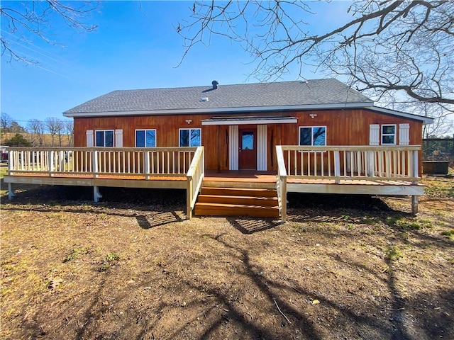 back of house featuring a wooden deck and roof with shingles