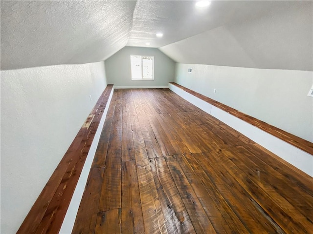 additional living space featuring baseboards, wood-type flooring, a textured ceiling, and vaulted ceiling