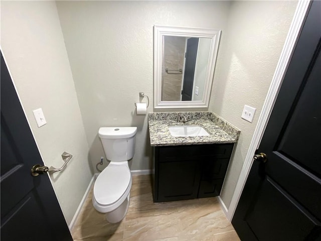 bathroom featuring baseboards, toilet, and vanity