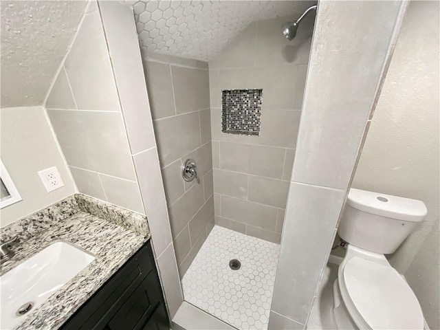 full bathroom featuring tiled shower, a textured ceiling, toilet, and vanity