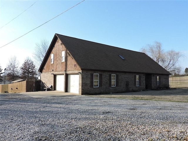 view of front of house featuring brick siding, roof with shingles, and fence