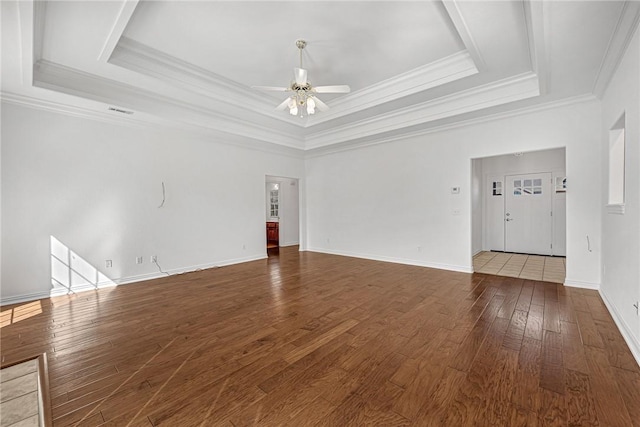 empty room with baseboards, a raised ceiling, hardwood / wood-style floors, and a ceiling fan