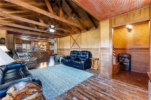 living area featuring vaulted ceiling with beams, wood finished floors, wood walls, and ceiling fan