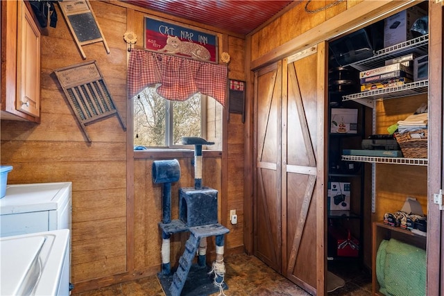 interior space with cabinet space, washer and dryer, and wood walls