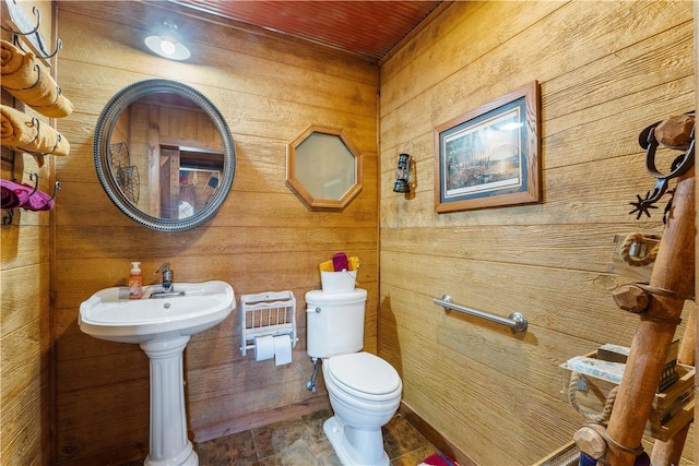 bathroom with wooden walls, wooden ceiling, and toilet