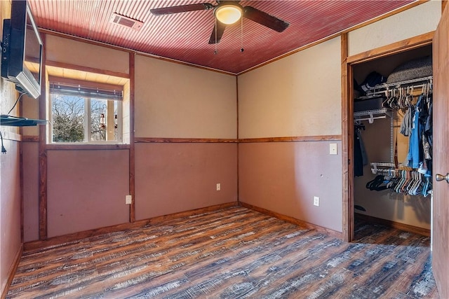 unfurnished bedroom with a closet, visible vents, a spacious closet, and wood finished floors