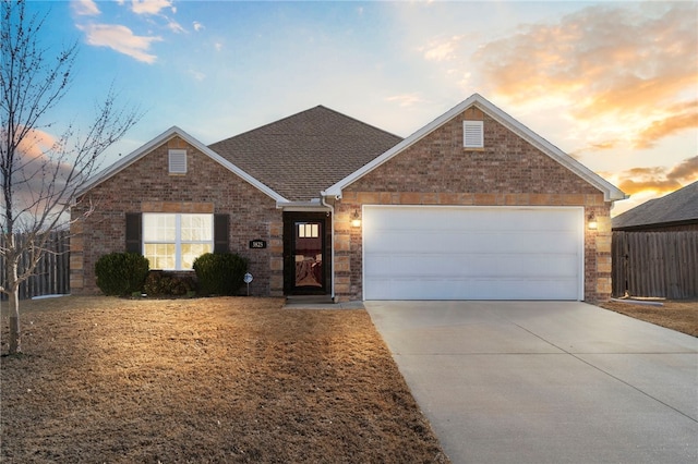 ranch-style home featuring brick siding, a shingled roof, fence, concrete driveway, and an attached garage