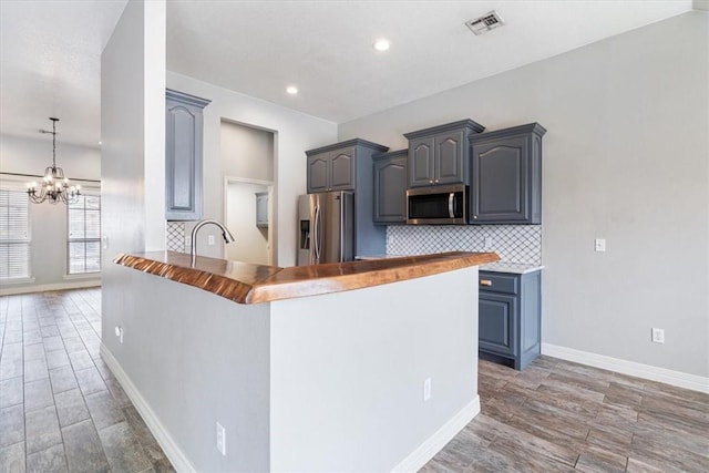 kitchen with an inviting chandelier, stainless steel appliances, backsplash, a peninsula, and recessed lighting