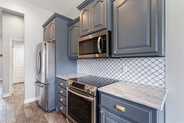 kitchen with light stone countertops, decorative backsplash, baseboards, and appliances with stainless steel finishes