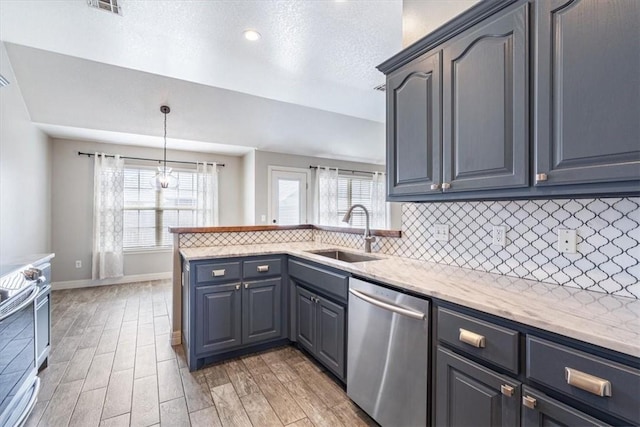 kitchen featuring a peninsula, light wood-style flooring, a sink, decorative backsplash, and stainless steel appliances