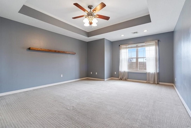 unfurnished room with a tray ceiling, baseboards, and light carpet