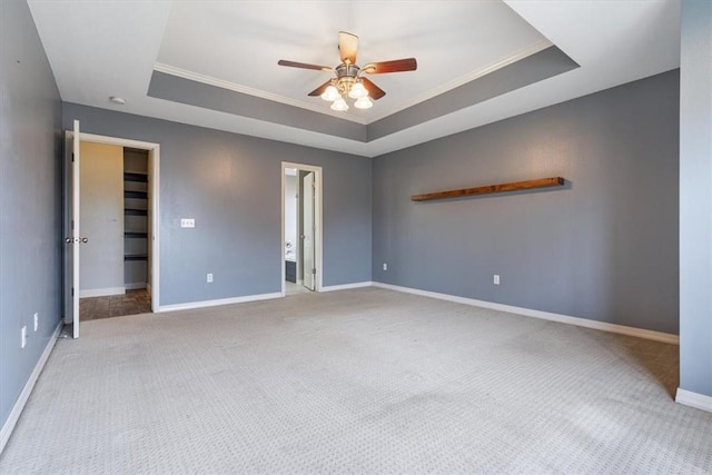 unfurnished room featuring ceiling fan, baseboards, a tray ceiling, ornamental molding, and carpet floors