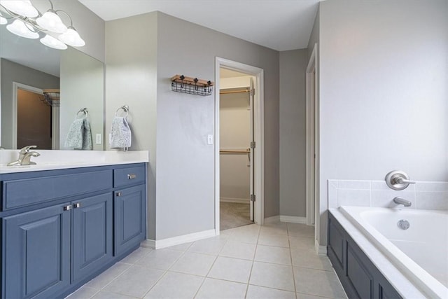 bathroom with a spacious closet, tile patterned flooring, vanity, a bath, and baseboards