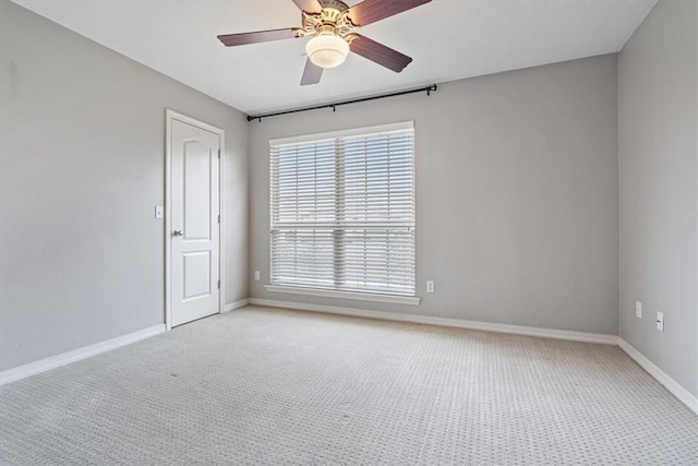 empty room featuring baseboards, light colored carpet, and a ceiling fan