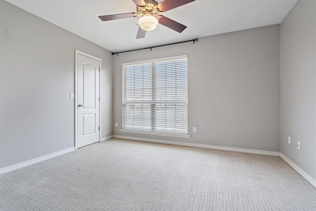 spare room featuring light colored carpet, baseboards, and a ceiling fan