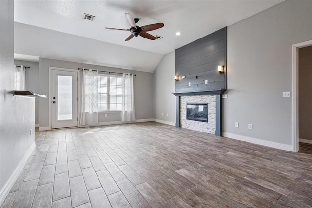 unfurnished living room featuring visible vents, wood finished floors, a large fireplace, ceiling fan, and vaulted ceiling