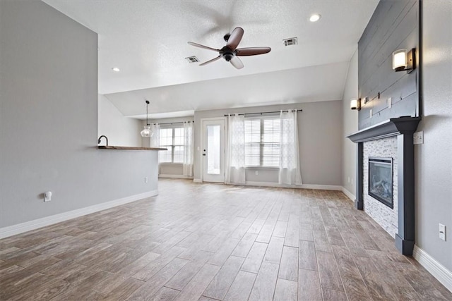 unfurnished living room with vaulted ceiling, visible vents, ceiling fan, and wood finished floors