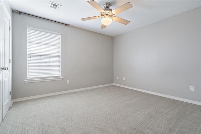 carpeted spare room featuring visible vents, baseboards, and ceiling fan