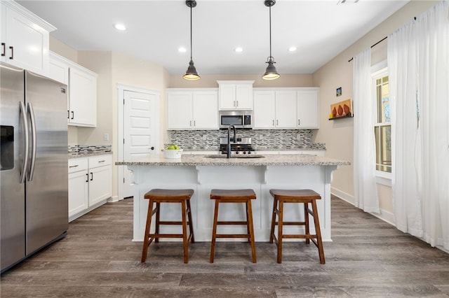 kitchen with dark wood-style flooring, appliances with stainless steel finishes, white cabinetry, and a sink